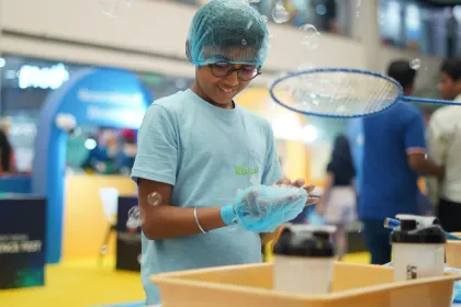 A child lifting a large bubble wand, bubbles drifting out across the atrium